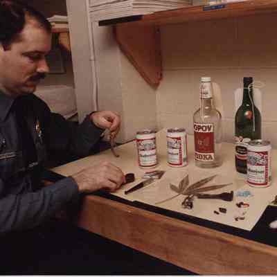 A photo view of police officer Brett Strout setting up a display on drugs. 1/30/1989.