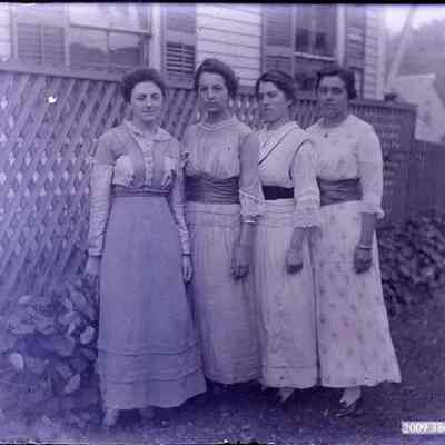 Four women standing (outside) .