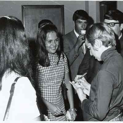 A B/W photograph of a member of the cast of Grease signing autographs.