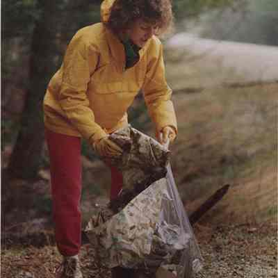 A photo view of a woman picking up trash. 5/3/1988.