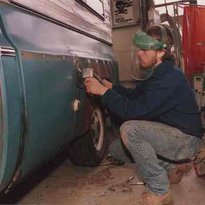 A photo view of a man doing body work on a pickup truck. 2/11/1987.