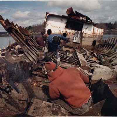 A photo view of 2 workmen cutting up an old boat. 4/19/1991.