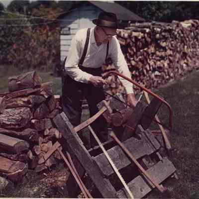 A photo view of a man sawing firewood. 8/3/1988.