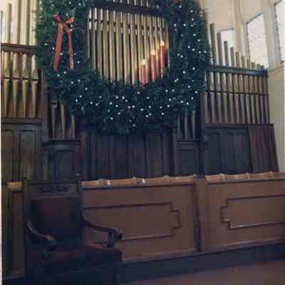 A photo view of a large Christmas wreath on an organ. 12/23/1988.
