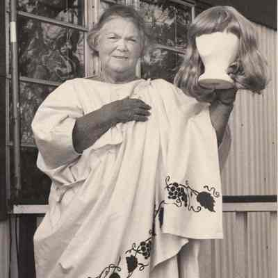 A photo view of a woman holding a wig. 11/7/1992.