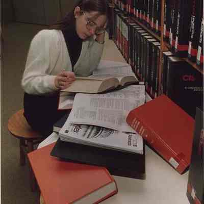 A photo view of a woman in a library. 12/16/1987.