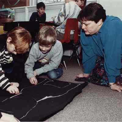 A photo view of 2 children playing and a woman watching. 1/17/1990.