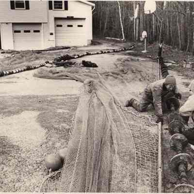 A photo view of 2 men repairing a shrimp net. 12/7/????