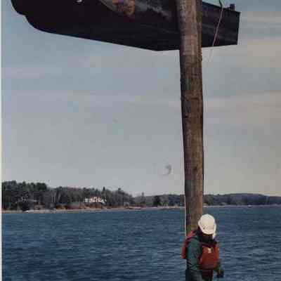 A photo view of two workmen hoisted by a crane. 4/15/1992.