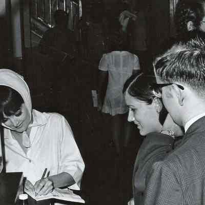 A B/W photograph of a member of the cast of Grease signing autographs.