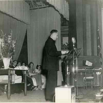 Father Dauphin at a Microphone