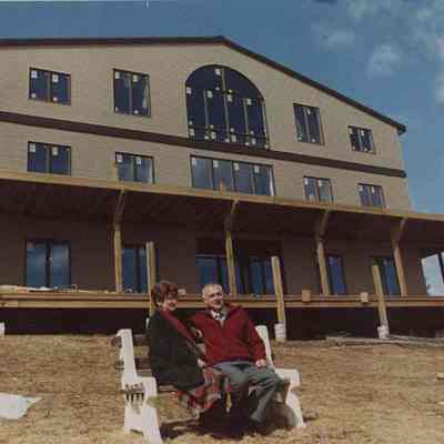 A photo view of a couple sitting in front of a new house. 4/1/1988.
