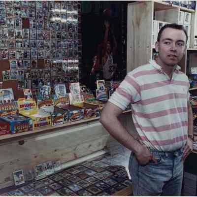 A photo view of a man and a display of baseball cards. 3/21/1990.