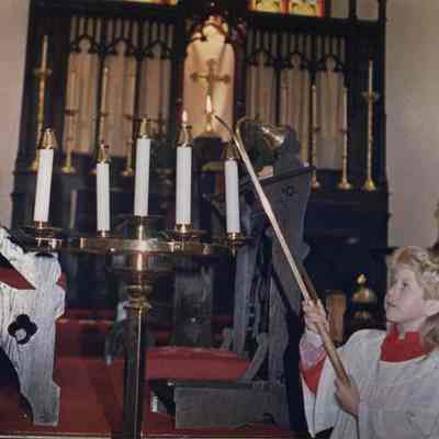 A photo view of a girl lighting candles in church. 12/9/1988.