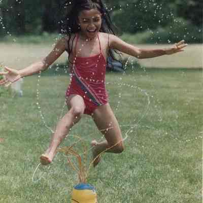 A photo view of a child playing in a water sprinkler. 6/23/1989.