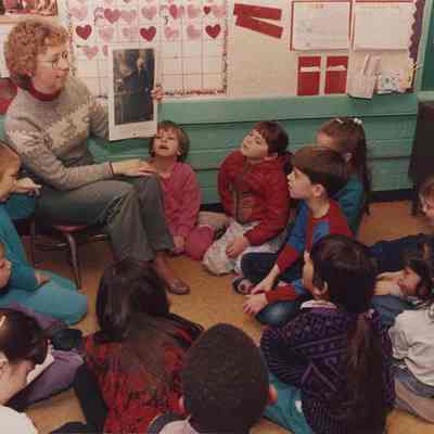 A photo view of a teacher and some school children. 2/23/1987.