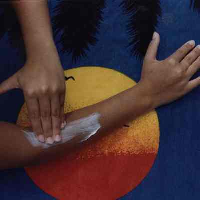 A photo view of someone putting on sun blocker. 7/3/1988.