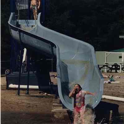 A photo view of children playing on a water slide. 7/01/1988.