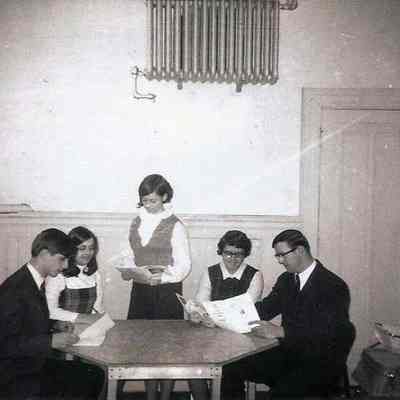 A B/W photograph of several people sitting around a table.