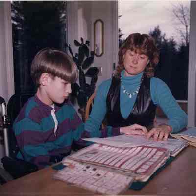 A photo view of a mother and child working at a table. 12/3/1990.