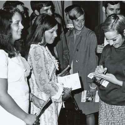 A B/W photograph of a member of the cast of Grease signing autographs.