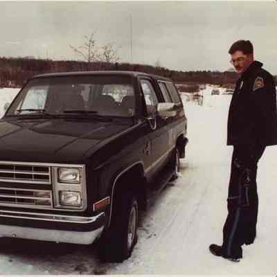 A photo view of a man looking at his stuck vehicle. 2/14/1990.