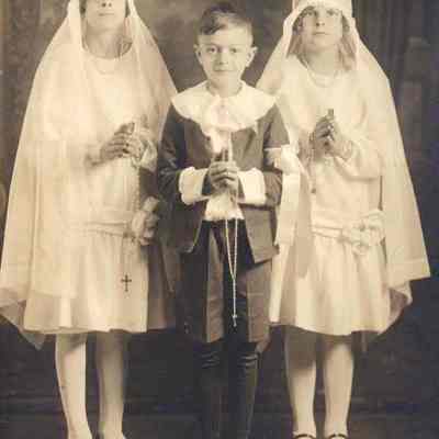 Two girls and a boy holding bibles and rosaries.