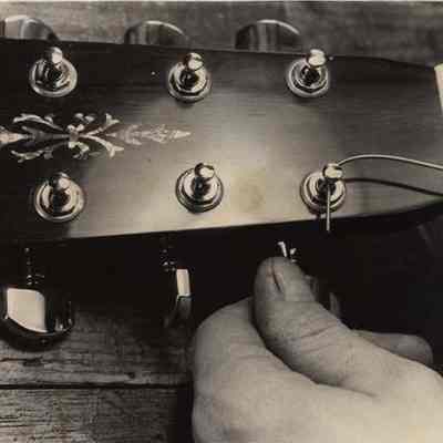 A photo view of David Bourgois stringing a guitar. 6/11/1984.