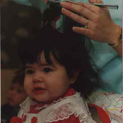 A photo view of a little girl getting her hair cut. 2/4/1988.