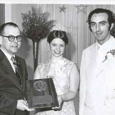 Sharon Hinckley is presenting the pageant award to Dick Tomko for his many years of service to the pageant while Gene Gagne is looking on.
