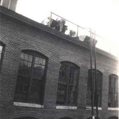 A photo view of workmen on the roof of the Pejepscot Mill.