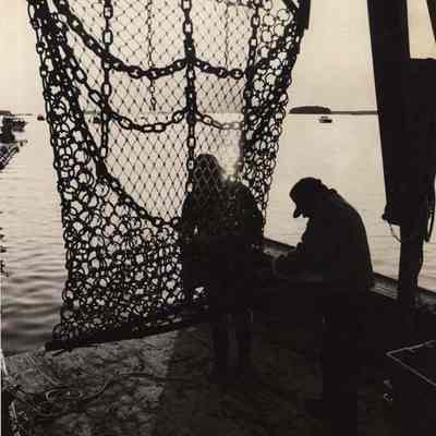 A photo view of two men securing a scallop drag.