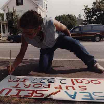 A photo view of a woman preparing a strike sign. 9/8/1989.