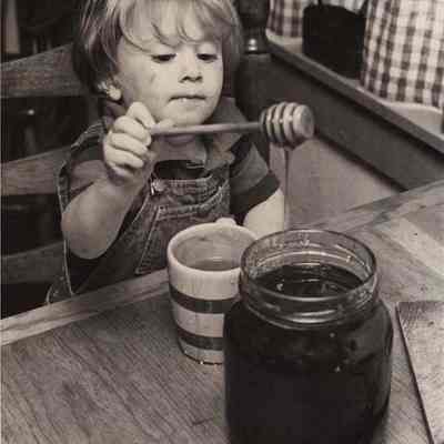 A photo view of Adam Clayman putting honey in his tea. 9/14/1981.