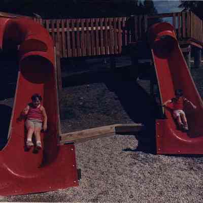 A photo view of two children on slides. 7/19/1988.