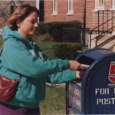 A photo view of a woman mailing a letter. 4/15/1987.