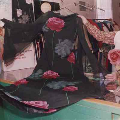 A photo view of two ladies holding a dress. 3/11/1987.