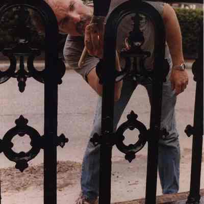A photo view of a man painting the fence on Green Street. 6/1/1989.