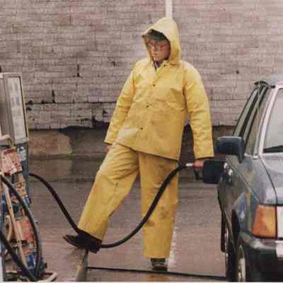 A photo view of a man putting gas into a car. 4/7/1987