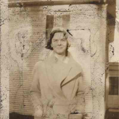 Unknown woman standing in front of a house.