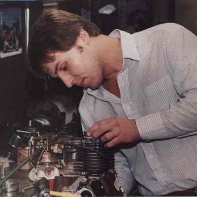 A photo view of a young man working on a small engine. 1/14/1987.