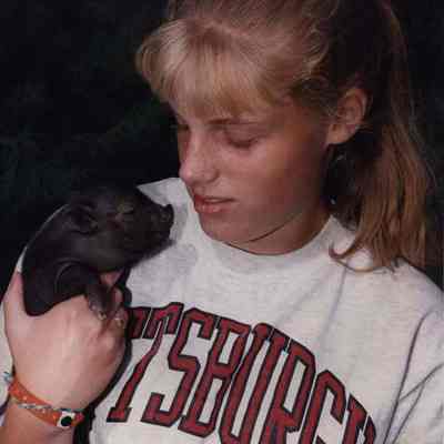 A photo view of a girl holding a baby pig