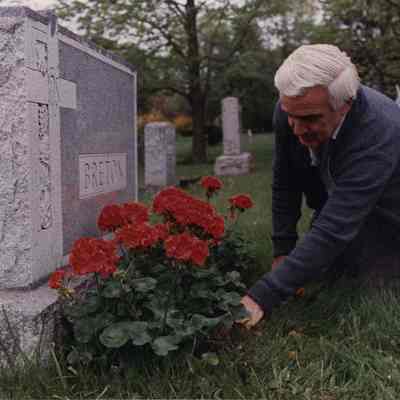 A photo view of a man putting flowers on a grave. 5/26/1989.