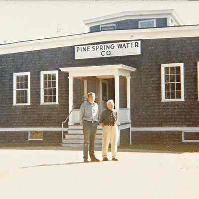 Two Men Standing in front of the Pine Spring Water Company Plant