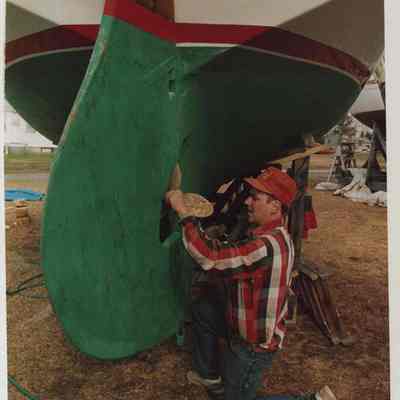 A photo view of a man working on a boat. 4/13/1987.