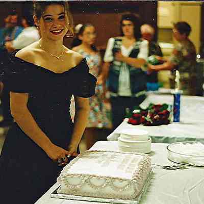 A color photograph of a girl and a cake.