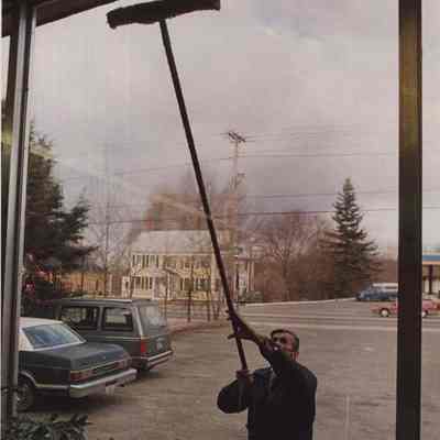 A photo view of a man washing windows. 12/15/1987.