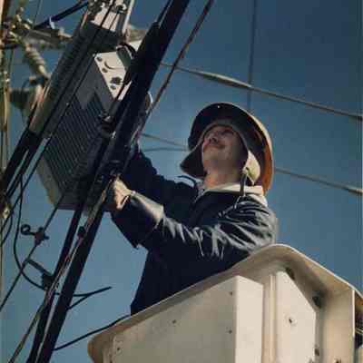 A photo view of a lineman working on some wires. 2/14/1991.
