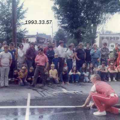 A photo of a man spraying a hose down a street. 9/15/1973