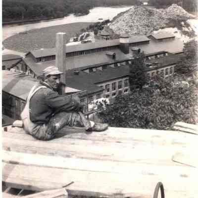 A photo view of a workman sitting at the top of the water tower.